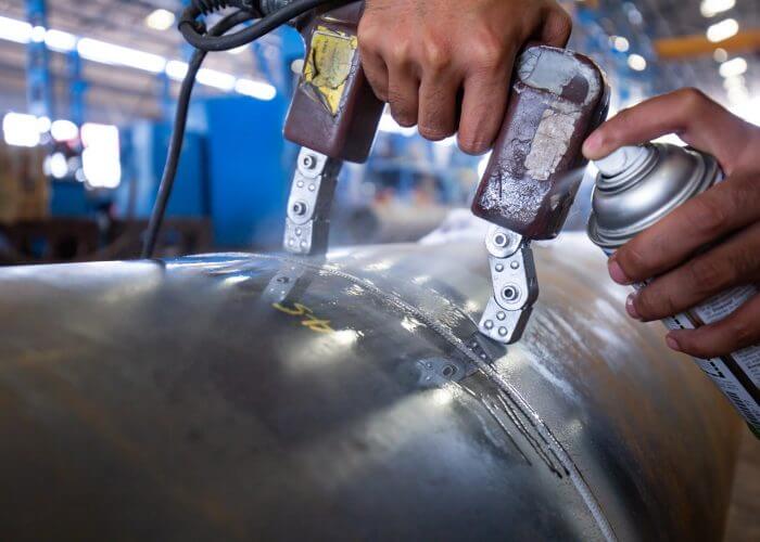 Magnetic-Particle-Inspection-Mpi Engineer conducting liquid penetrant examination on duplex steel plate for defects